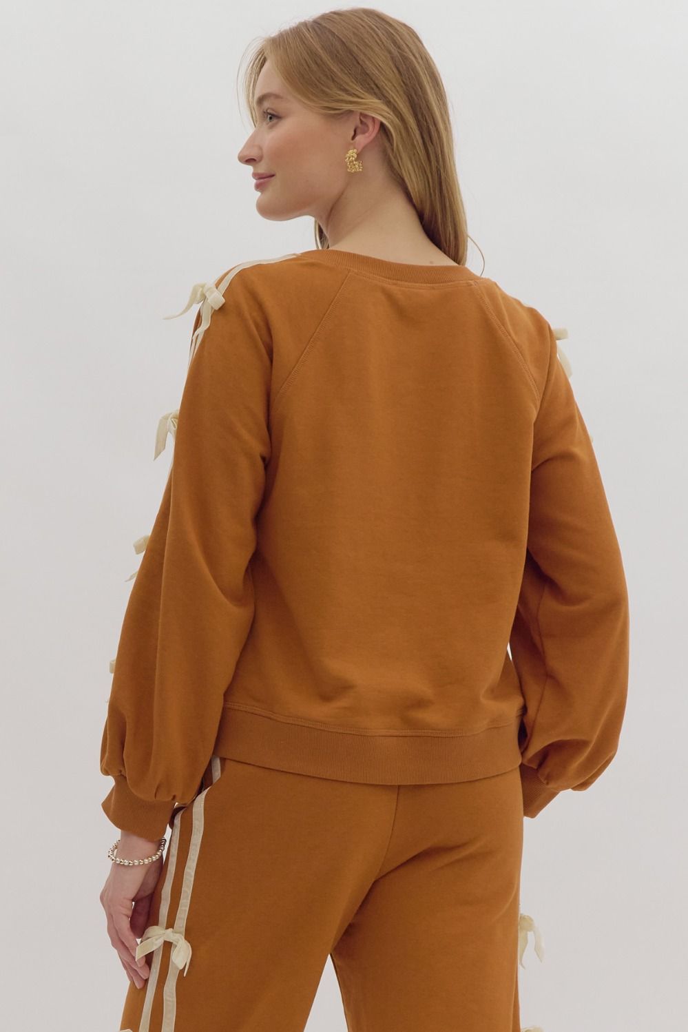 +Solid long sleeve cropped pullover featuring contrasting solid trim detail at side. Bow detail at side.